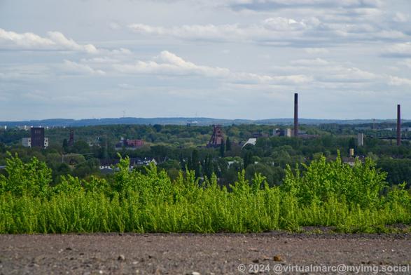A view from a hill to the distance in the direction of the City Essen where you can see the Doppelbock of the coal mine Zollverein and part of the coking plant Zollverein.
