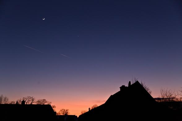Picture of the evening twilight sky with the Moon and Venus. The sky is dark blue and slightly orange near the horizon.