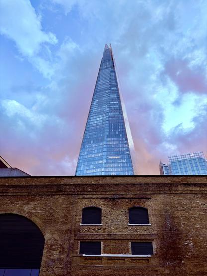 A view of the Shard building in London with light glowing amber on its back shot during the magic hour
