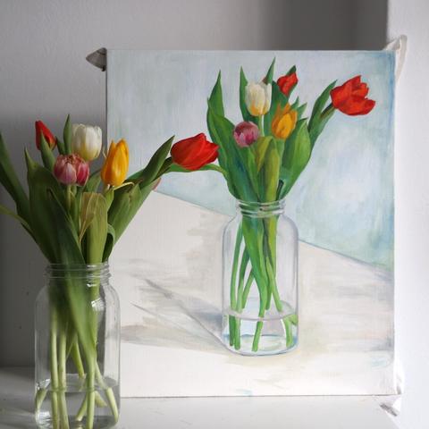 In the background there is an oil painting of a vase with flowers. In the front you can see the model: a glass vase with six tulips.