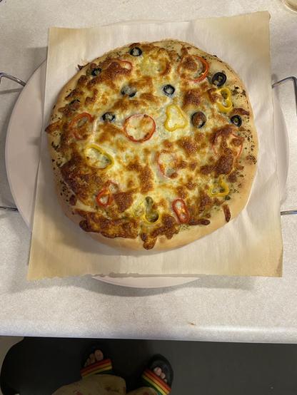 Homemade pizza with sweet peppers, olives and cheese baked to perfection on a pizza stone