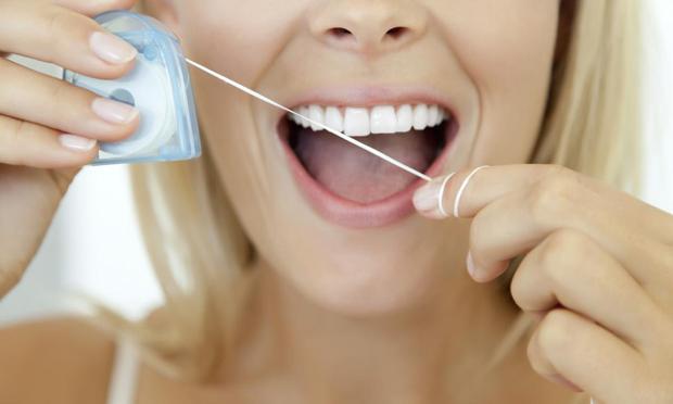Una imagen de archivo de una mujer a punto de usar el hilo dental (Getty Images/PhotoAlto)