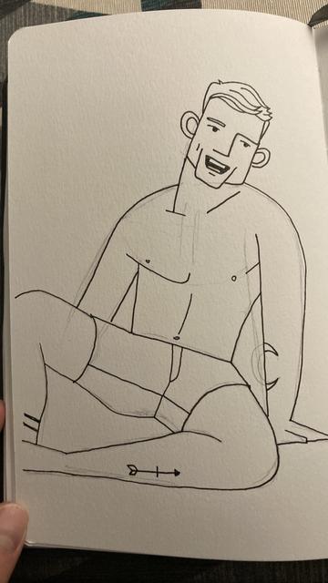 Dibujo a tinta sobre papel de un hombre joven y atlético, con el torso desnudo y usando pantalones cortos. Está sentado en el suelo, apoyándose con una mano detrás de él y con una expresión sonriente. La ilustración es un boceto con líneas definidas y algunos trazos de construcción visibles. En su pierna, cerca de la rodilla, tiene un pequeño tatuaje de una flecha. El papel tiene textura y la imagen está tomada desde un ángulo ligeramente inclinado.