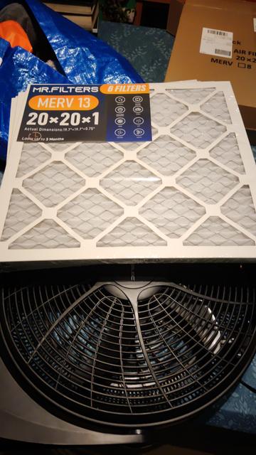 A stack of white, square MERV13 filters (basically a 20" x 20" x 1" card box with open sides, containing cloth like filter material).

It lies in top of a black 20" circular fan, covering about half of it.