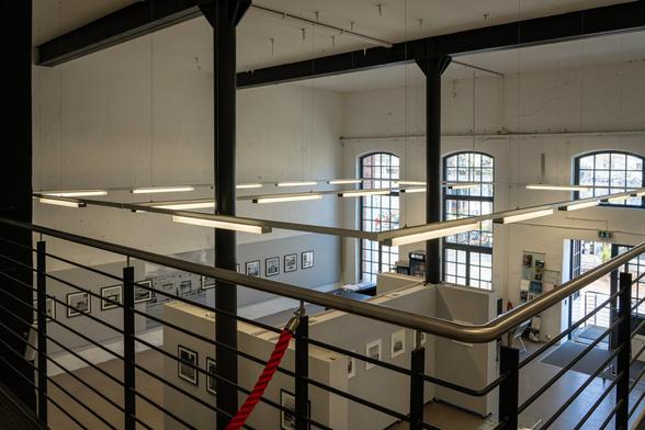Erhöhte Draufsicht auf den Ausstellungsraum der GAF. Fenster, Lichter und Fotos sind zu sehen.