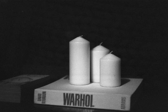 three white candles suit on a coffee table book of Warhol's art