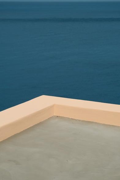 a corner of a flat roof, in pink plaster, In a minimal picture with the vastness of the sea as the background