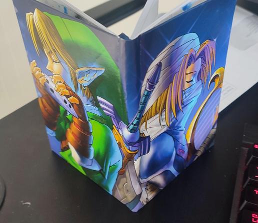 Hardcover booklet, with as cover on the front side Sheikh from Zelda games playing a lyre, and on the back side link playing an ocarina.