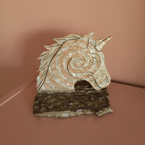Grey stoneware ceramic unicorn sculpture with a swirling pattern on a unicorn with an angry expression.