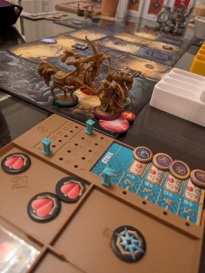 A table with a spread-out board game, plastic miniatures on a printed dungeon map