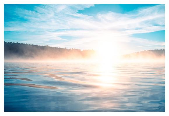 Landscape photography of a calm lake in the morning, reflecting golden sunlight, surrounded by nature, with the sun casting a warm glow on the surface of the water.