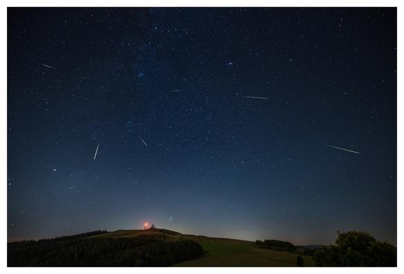 The picture shows a meteor shower over the Wasserkuppe, the highest mountain in the Rhön, a low mountain range in Germany.