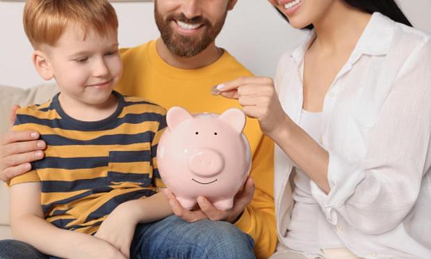Imagen de archivo de una familia poniendo dinero en una hucha. (Getty Images)