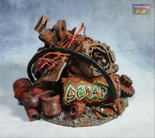 A pile of rusty metal. Graffiti on one piece says "Scrap".