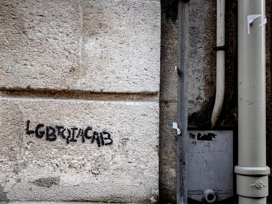 Cement wall with spray painted letters “LGBTQIACAB”