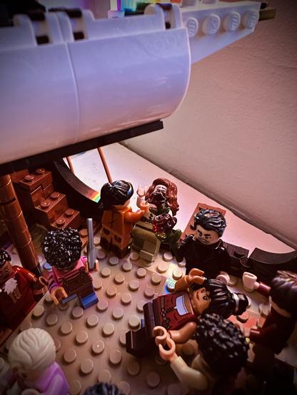 Lego Mary shoves Lego Anne over the edge of the ship. Lego Roach brandishes a clever. Lego Jim catches Lego Archie, who has been pushed. Lego Izzy looks pissed while holding a glass rose.