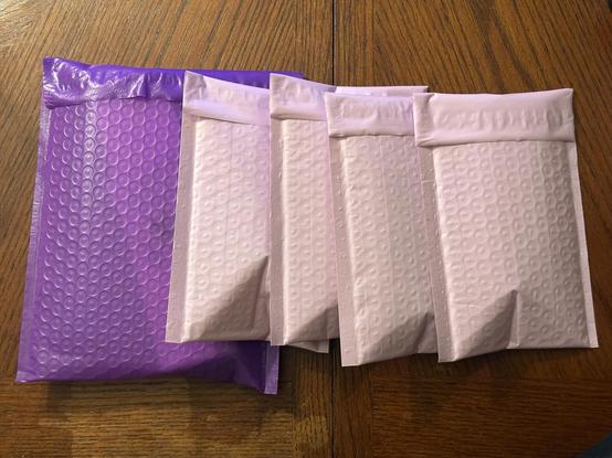 Five closed bubble mailers lined up on a wood table