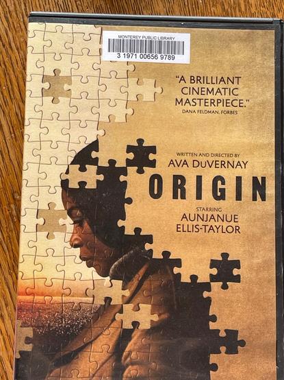 DVD cover for “Origin,” written and directed by Ava DuVernay; “a brilliant cinematic masterpiece” (wrote Dana Feldman, Forbes) starring Aunjanue Ellis-Taylor. The art is a profile of the face of a Black woman, includlng her upper body; her image is part of a jigsaw puzzle; the back of her head is not visible, and some puzzle pieces are placed on her head and shoulder.