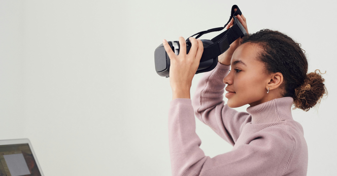 weiblich gelesene Person setzt eine VR-Brille auf