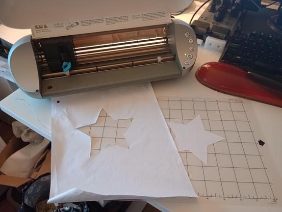 the Portrait with a cutting mat and a piece of printer paper, with a star shape cut into the paper