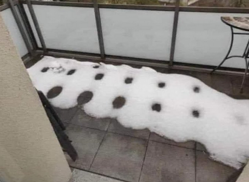 Black and white image of snow melting on outdoor patio tiles. Image shows that the snow melts more quickly at the junction of the tiles to each other at the corners, where they all meet at angles of 90 degrees.