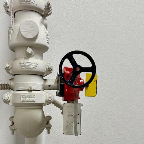 White pipe in an apartment building, presumably for fire control, but who knows because I’m not a pipe scientist. While almost everything is white, the end features a black wheel, red box, and yellow tag of sorts.