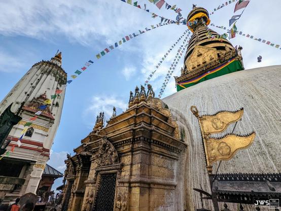 This photo shows the Swayambhunath temple complex in Kathmandu, Nepal. The main structure of the monument is a stupa (or chaitya), which is a mound-like structure that contains relics or sacred objects. In this case, the relics are supposed to be parts of Buddha's body and hair. 

The complex also has several shrines and temples dedicated to various deities, including the Hindu god Shiva. The site is considered one of the most important Buddhist pilgrimage sites in Nepal and attracts thousands of visitors every year.

In addition to its religious significance, Swayambhunath is also known for its stunning architecture and beautiful surroundings. The stupa itself is surrounded by a series of terraces, which are adorned with intricate carvings and statues. The site is also home to several other important structures, including the Mahabihar (Great Monastery) and the Changu Narayan temple.

Overall, Swayambhunath is an important cultural and historical landmark in Nepal, and its significanc