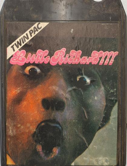 A photo of a vintage black plastic 8-track cartridge tape entitled "Twin Pac" by Little Richard, stylised as Little Richard!!! Inset photo is a close up of Little Richard, wide-eyed and singing (or pulling an o-face).