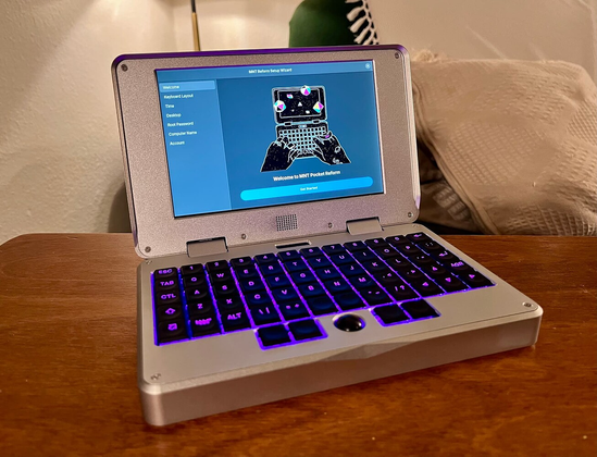 an open silver colored mnt pocket reform with a glowing purple keyboard on a table