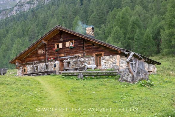 The photograph shows a large, old mountain farm building.