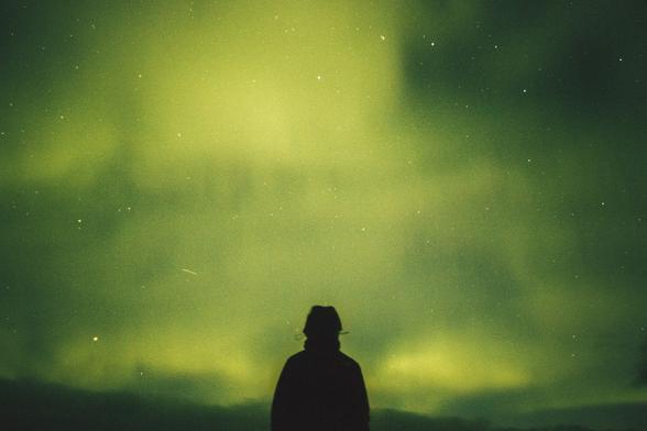 Unsplash photo shows the back of a person at the center bottom of the frame, shown from the waist up, facing away from the camera. They are in silhouette and nearly black. In the distance where they are facing, and filling up the whole picture, are the green curtain-like undulations of the diaphonous Aurora Borealis, also known as the Northern Lights. Through the greenish sky we can also make out a number of stars. Mood is one of awe of Nature. 
Captioned, "person standing under green aurora borealis ... watching in Breiðavík, Iceland by Ihor Malytskyi (@ihor_malytskyi)". 

Breiðavík, Iceland. 
Dated 2017 Oct 24, by Ihor Malytskyi. 
www.Unsplash.com/photos/person-standing-under-green-aurora-borealis-YvctEBM0W1g 

🔗 https://KronoMoon.org 🏳️‍🌈 ☮️ 
#Kronodon