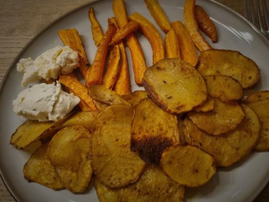 Teller mit gebackenen Möhrenstreifen, Kartoffelscheiben und Frischkäse