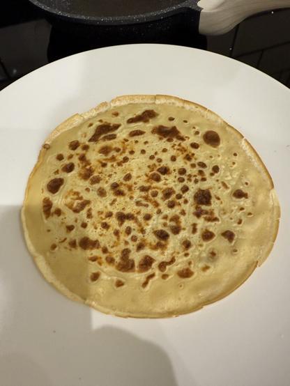 A pancake on a white plate.
