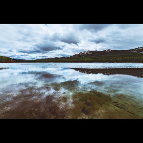Landscape photo in color, from British Columbia in Canada.Ths is a lake with ice, with reflection of a mountain