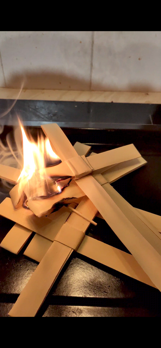 A baking tray full of palm crosses. They are aflame.