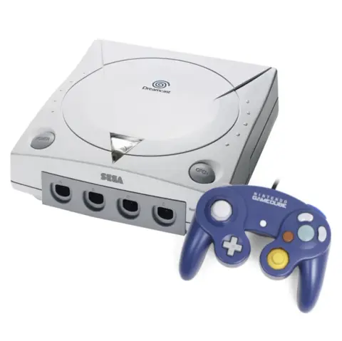 An GameCube controller next to the white Sega Dreamcast console