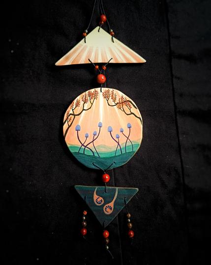 Suspension décorative en argile peinte à l'acrylique avec des perles, représentant l'automne avec des arbres aux feuilles oranges, des champignons et des petits insectes qui dorment sous la terre.