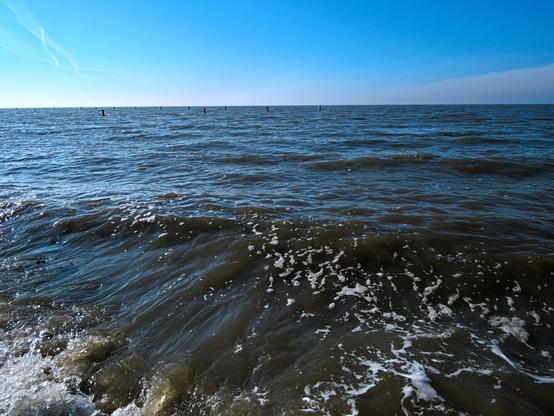 Most of the picture shows the sea, the North Sea to be precise. It is high tide, the water is dark and there is a strong movement directly in front of me. The sky is cloudless, it's a sunny day. I love the vastness.