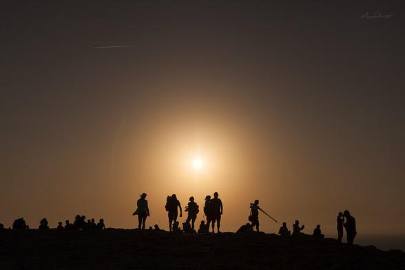 Jendea mendi baten magalean elkarrekin eguzkia zeruan dagoela