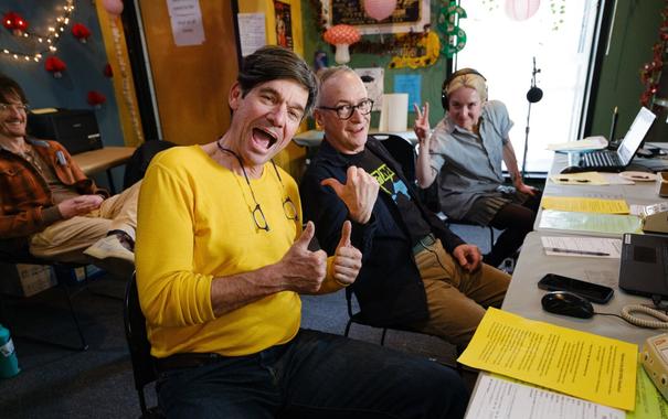 The phone volunteers in the front row and emcee Jody Peyote mug for the camera.  There are big smiles, thumbs, and a peace sign.  The volunteer behind them smiles quietly but widely.