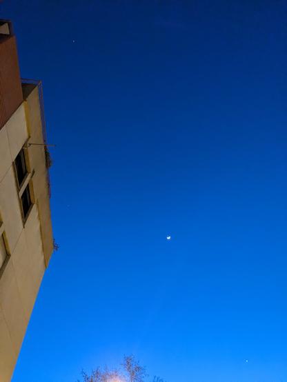 A deep blue twilight sky with three little bright dots: Jupiter, the moon, and Venus. The ugly concrete facade of my building is at left!