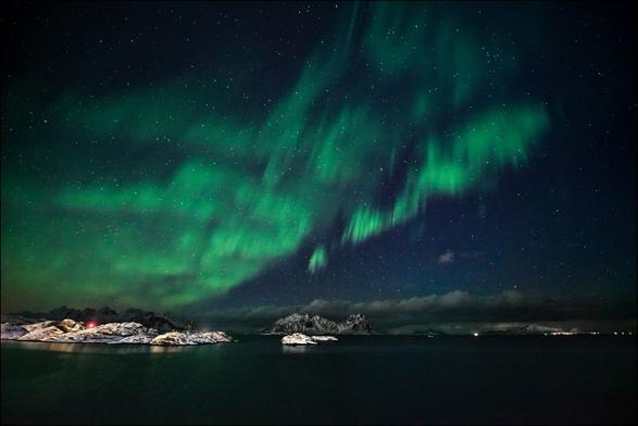 Polarlichter über Felsen im Meer auf den Lofoten in Norwegen.