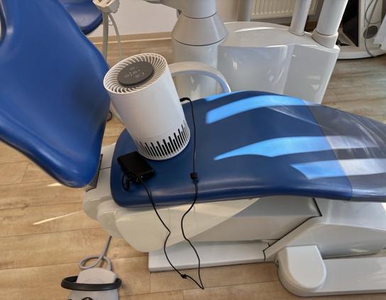 Ein mobiler Luftreiniger auf einem Behandlungsstuhl in einer Zahnarztpraxis mit 12V PD Triggerkabel und 20k Powerbank.
