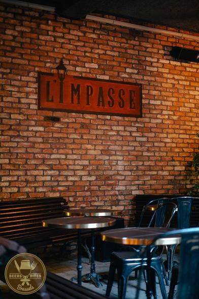 the interior of l'impasse with some chairs and tables, and a big plaque of L'impasse on the wall