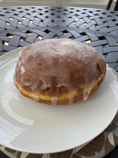 One of the special donuts sits on a white plate.  It is coated with a crisp layer of sugared icing (but not too much.) and is filled with creme.

I wanted to take a photo after a bite was taken out, but was overruled.