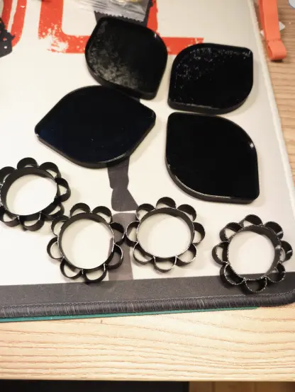 8 Teile des Hula Systems aus schwarzen TPU liegen auf einer hellen Schreibtischunterlage.