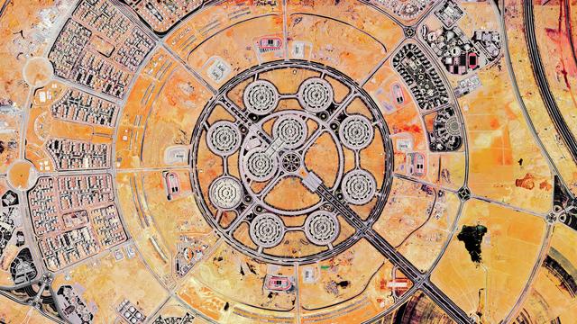 A satellite picture of a very geometric landscape consisting of concentric circles streets crossed diagonally by big roads. In the center, a circular pattern of 8 octogonal buildings forming the ministry of defense in New Cairo.