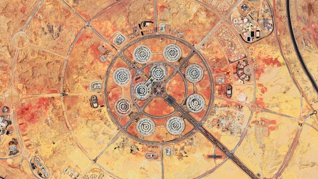 A satellite picture of a very geometric landscape consisting of concentric circles streets crossed diagonally by big roads. In the center, a circular pattern of 8 octogonal buildings forming the ministry of defense in New Cairo. The whole project is surrounded by construction sites and empty plots of land, as it is not yet finished at this stage.