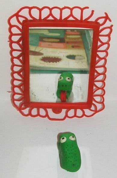 Un « mou » en pâte fimo qui tire la langue devant un miroir.