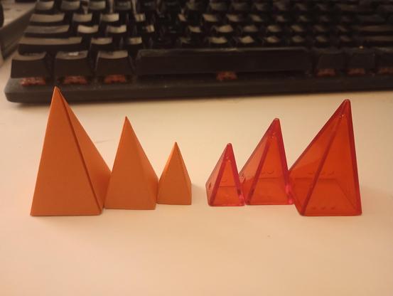 a complete set of papercraft pyramids, next to the originals.